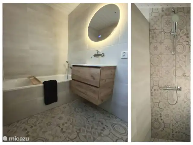 De badkamer met ligbad, separate douche en wastafelmeubel